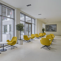 Bright yellow modern chairs with sleek black bases in a light-filled, minimalist lounge setting.