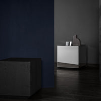 "Minimalist black and white furniture against a dark blue wall, featuring sleek, modern lines and a polished finish."