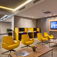 Bright yellow chairs with sleek lines and modern design, set against neutral tones and wooden accents in a stylish lobby.
