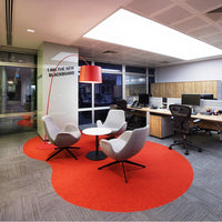 Modern office with a striking red circular rug, gray patterned carpet, and sleek white furniture.