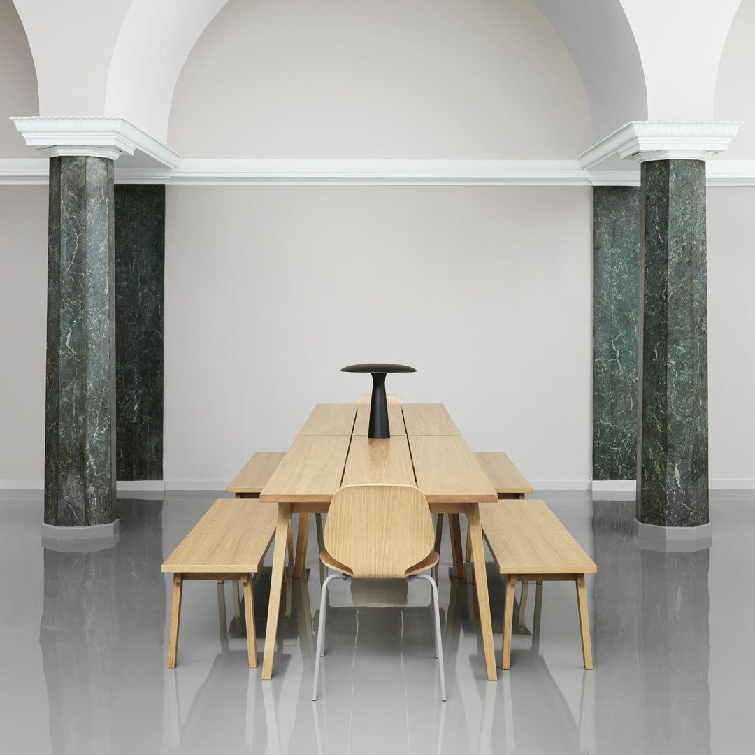 Light wood dining table set with sleek lines, complemented by minimalist black accents and gray polished floor.