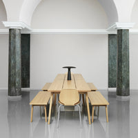 Light wood dining table set with sleek lines, complemented by minimalist black accents and gray polished floor.