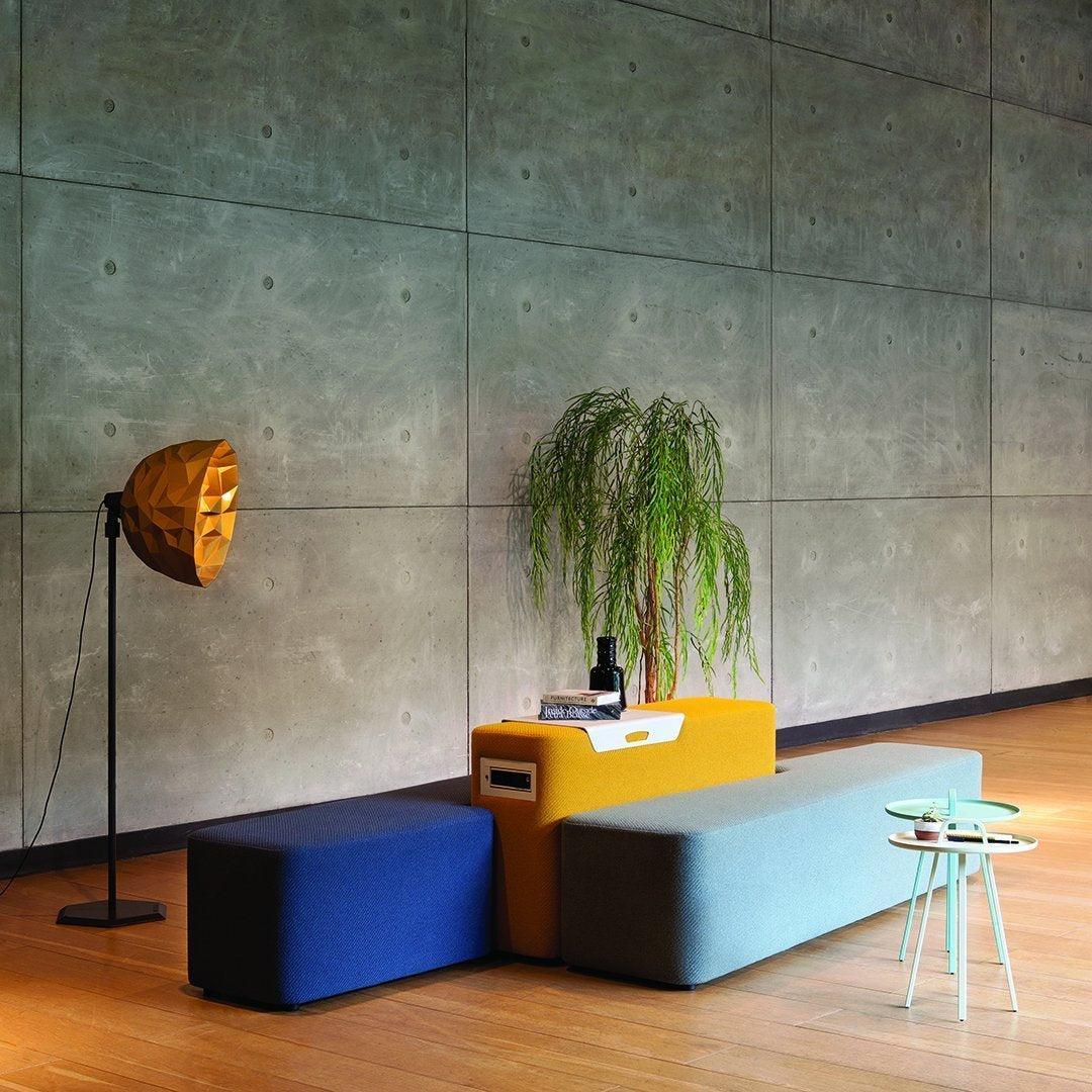 Colorful modular seating in blue, gray, and yellow, complemented by a sleek green accent table and metallic lamp.