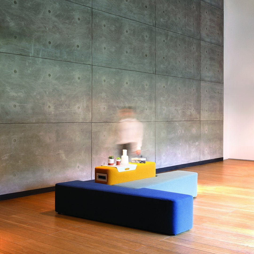 Modern blue and yellow seating with a sleek design, set against a textured concrete wall.