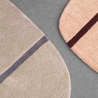 Soft beige and peach rugs with contrasting gray and burgundy stripes, showcasing modern, curved patterns.