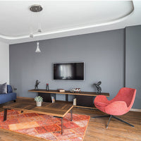 Modern living room with a gray wall, red accent chair, and a vibrant orange and cream patterned rug.