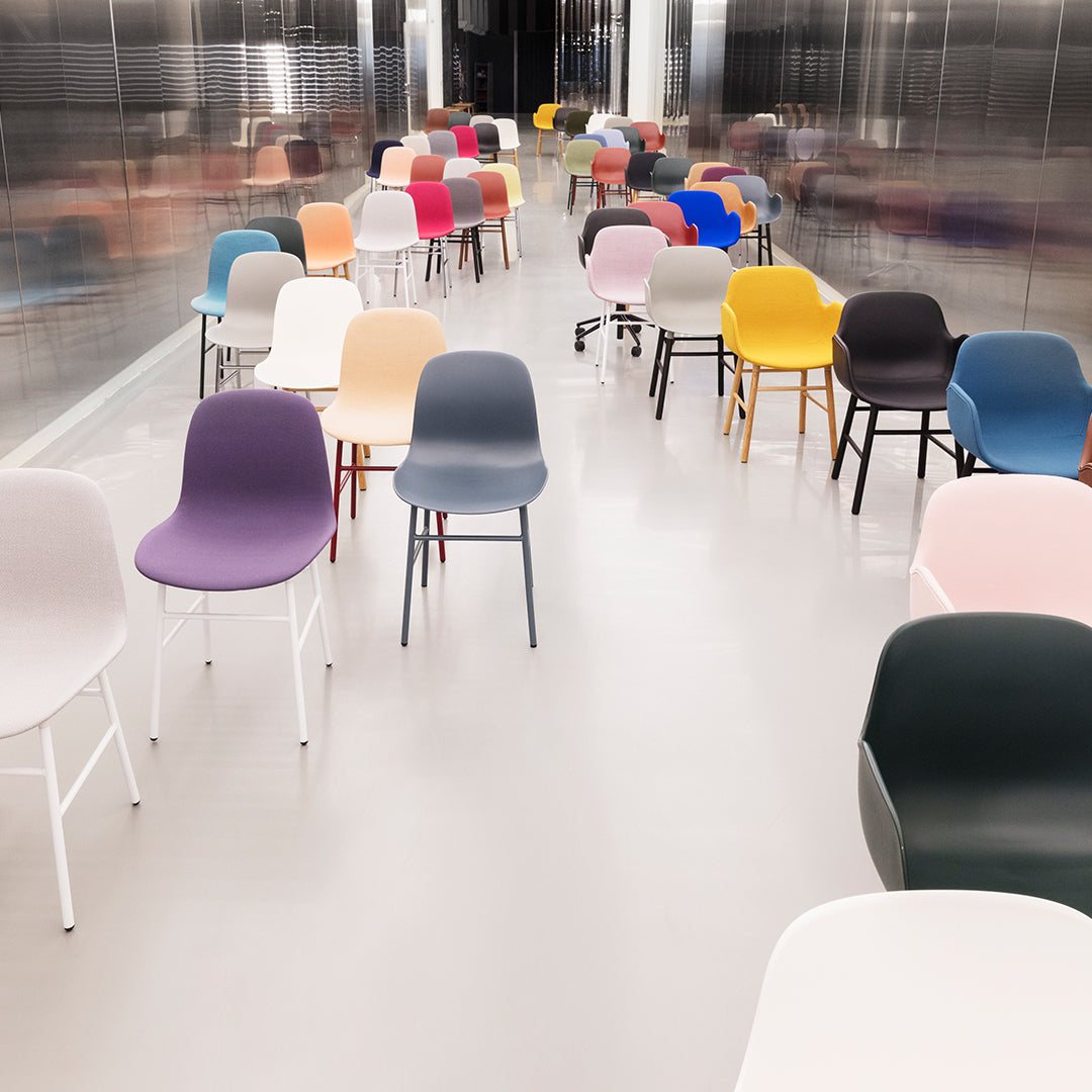 Colorful modern chairs in various shades, including pastel pink, purple, yellow, and dark gray, arranged in a sleek space.