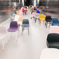 Colorful modern chairs in various shades, including pastel pink, purple, yellow, and dark gray, arranged in a sleek space.