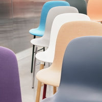 Colorful stackable chairs in pastel shades of blue, white, peach, purple, and gray against a metallic background.