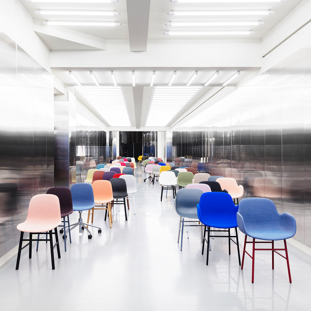 Colorful chairs featuring various hues like pink, blue, and yellow, arranged in a modern, minimalist setting.