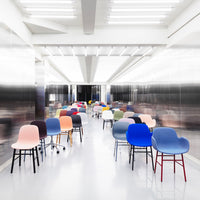 Colorful chairs in various shades, including pink, blue, yellow, and purple, arranged in a sleek modern space.