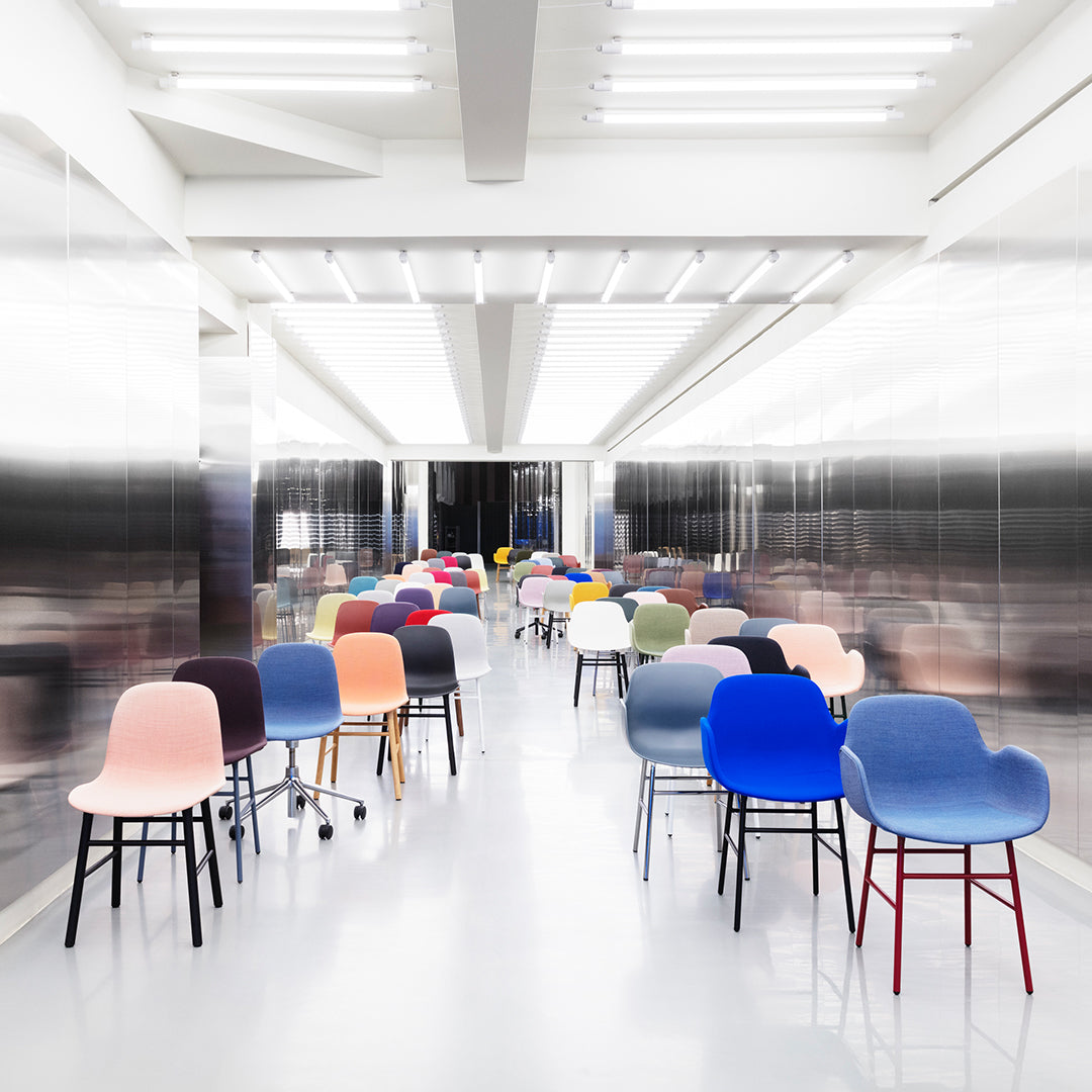 Colorful chairs in various shades, including pink, blue, and grey, arranged in a modern, sleek interior setting.