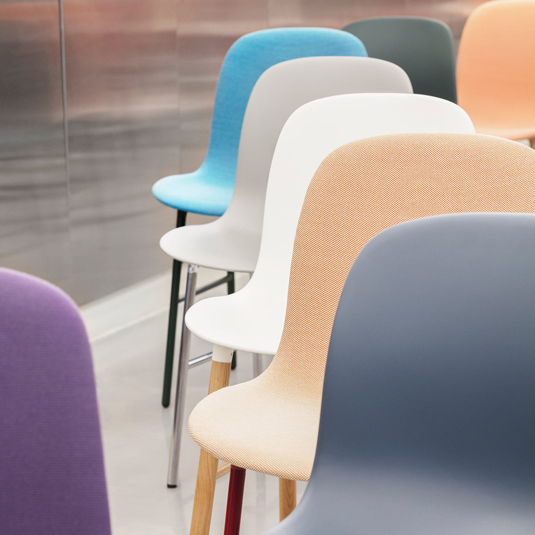 Colorful stackable chairs in pastel shades of blue, white, peach, purple, and gray against a metallic background.