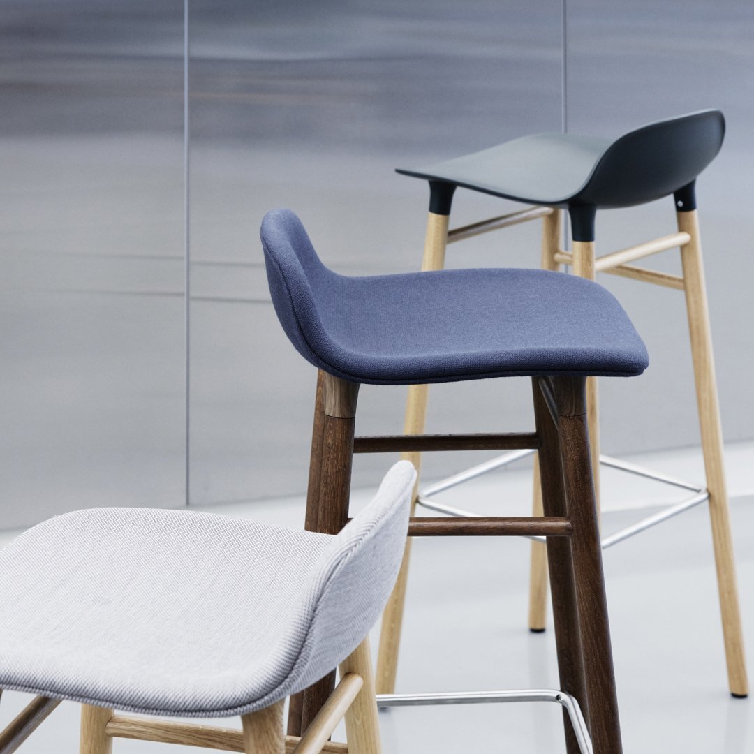 Stylish bar stools in gray, navy, and black with sleek wood and metal legs, perfect for modern decor.