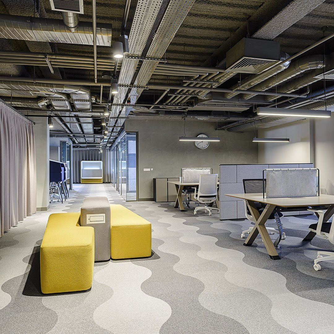 Modern office space featuring yellow seating and wavy gray carpet patterns, creating a vibrant, stylish atmosphere.