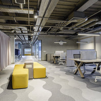 Modern office space featuring yellow seating and wavy gray carpet patterns, creating a vibrant, stylish atmosphere.