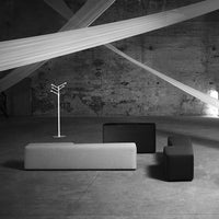 Black and gray modern sofas in a minimalist industrial space with intersecting white lines overhead.
