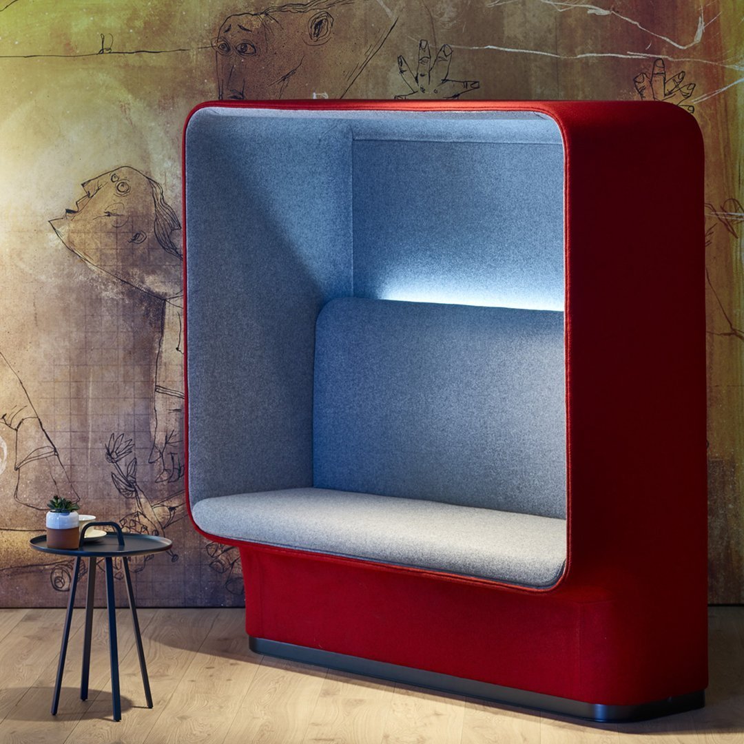 Red upholstered booth with a soft gray interior and subtle lighting, set against an artistic backdrop.