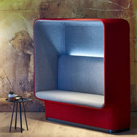 Red upholstered booth with a soft gray interior and subtle lighting, set against an artistic backdrop.