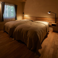 "Soft beige bedding with subtle texture, complemented by warm wooden accents and peaceful natural lighting."