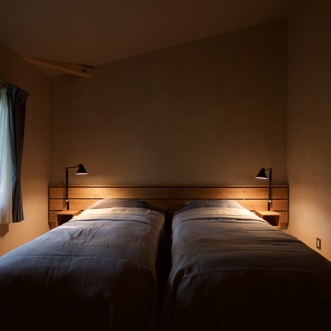 "Cozy twin beds with soft gray bedding, warm wood accents, and ambient lighting in a serene, muted color palette."