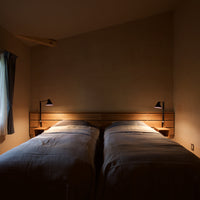 "Cozy twin beds with soft gray bedding, warm wood accents, and ambient lighting in a serene, muted color palette."