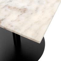Light-colored marble table surface with subtle beige veining, paired with a sleek black round base.