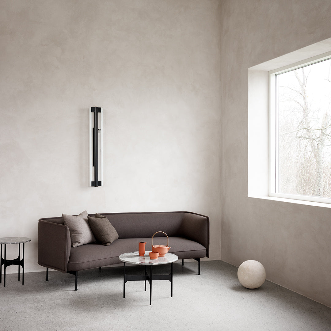 Modern brown sofa with plush cushions, paired with a minimalist round table in neutral tones and terracotta accents.