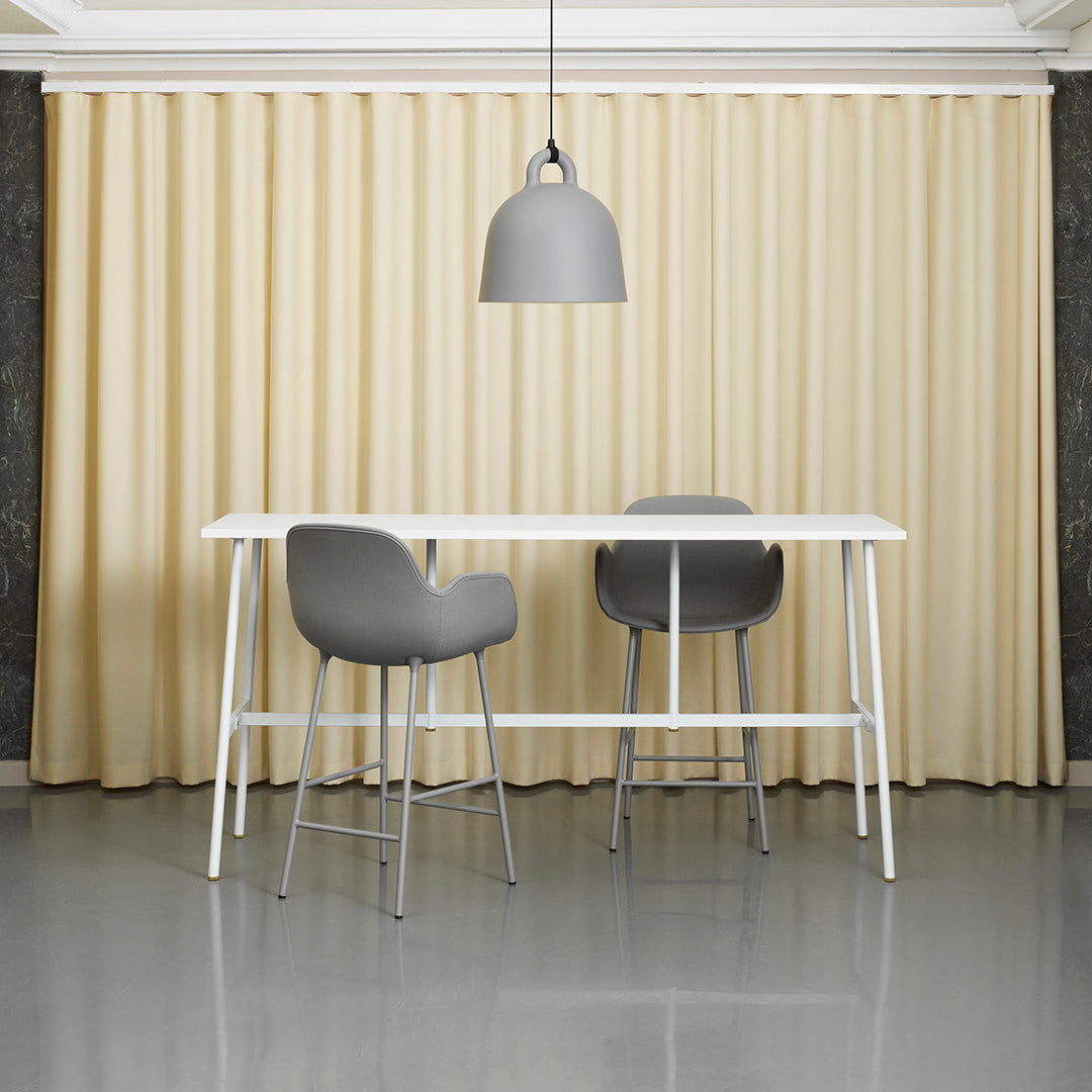 Beige curtains softly draping behind a modern white table and gray bar stools in a sleek, minimalist setting.