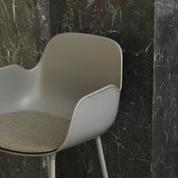 Stylish grey plastic chair with beige seat cushion, complemented by a dark textured marble background.