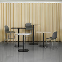 Modern furniture set with sleek black tables and gray chairs against a soft yellow curtain background.