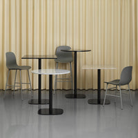 Modern furniture display featuring black and white tables with gray chairs against a soft yellow curtain backdrop.