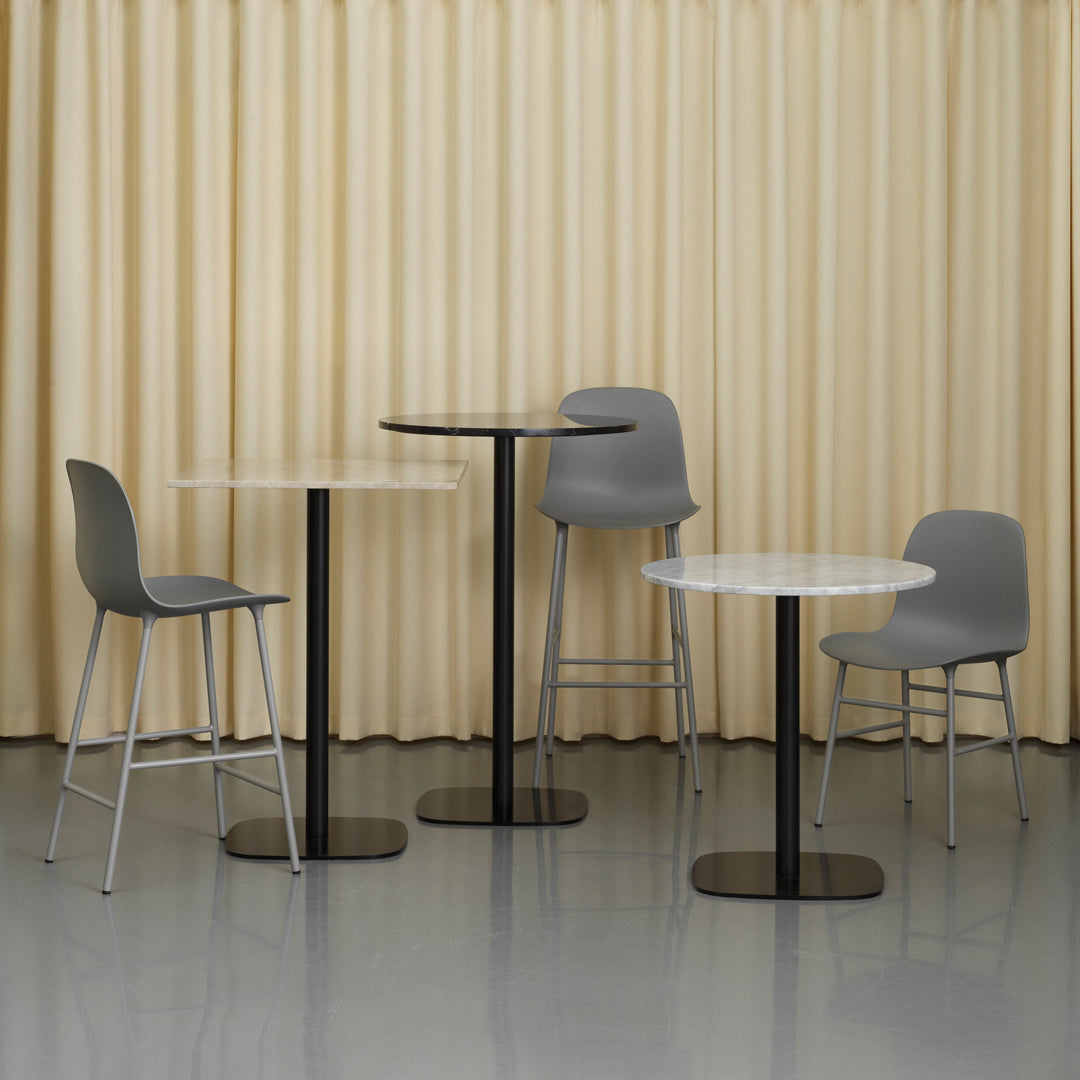 Modern furniture set featuring grey chairs and tables with white tops and sleek black bases against a beige curtain backdrop.