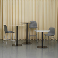 Modern furniture set featuring grey chairs and tables with white tops and sleek black bases against a beige curtain backdrop.