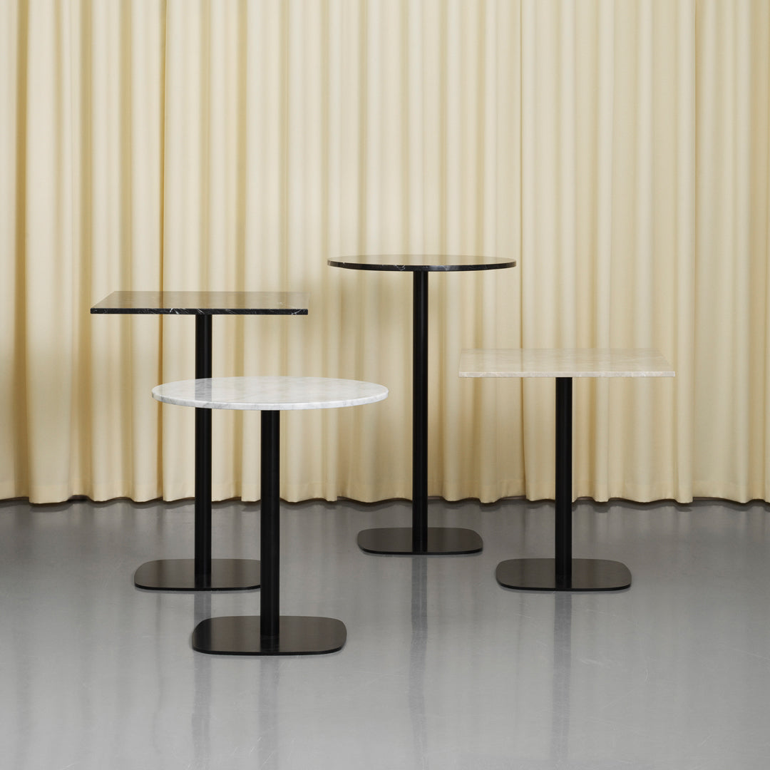Four modern side tables in black and white, featuring sleek, minimalist designs with round and square tops.