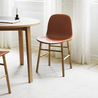 "Modern chair in earthy terracotta with natural wood legs, set against a light, minimalist backdrop."