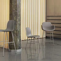 Gray chairs with smooth, modern designs against a soft yellow curtain and glossy floor, featuring minimalist lines.