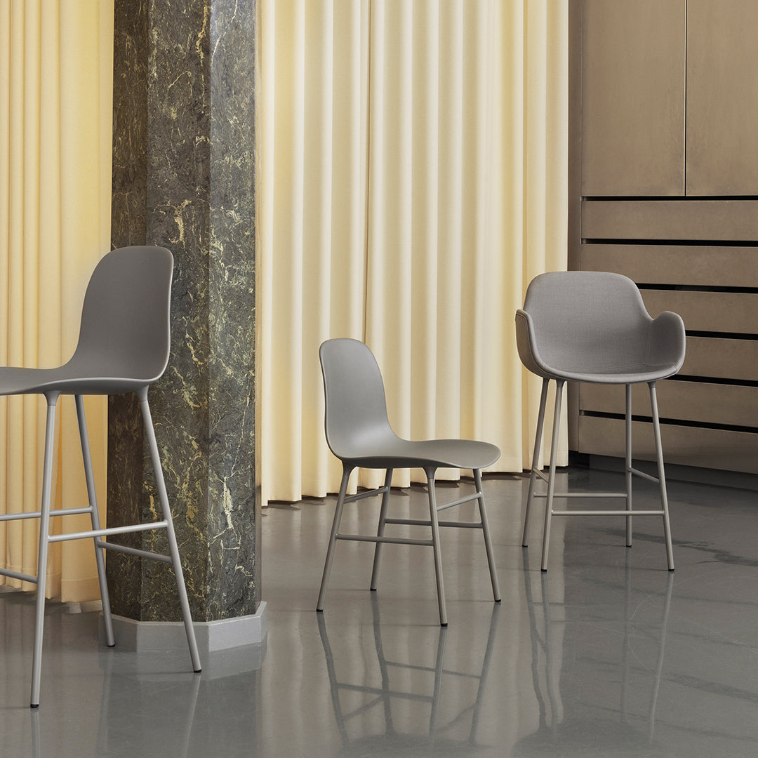 Gray modern bar stools with smooth curves and minimalist design against a warm beige backdrop and glossy floor.