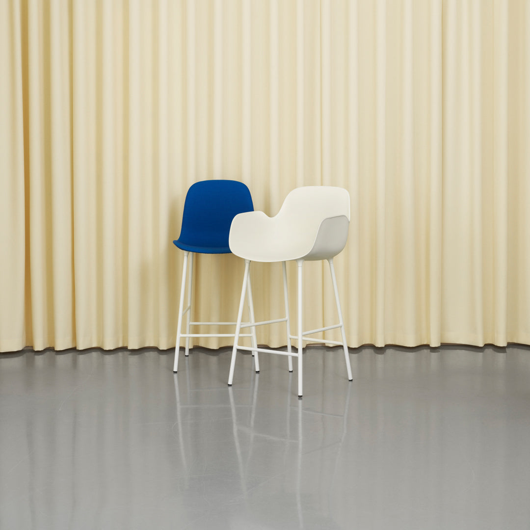 Blue and white modern barstools against a soft yellow backdrop with smooth textures and minimalistic design.