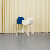 Blue and white modern barstools against a soft yellow backdrop with smooth textures and minimalistic design.