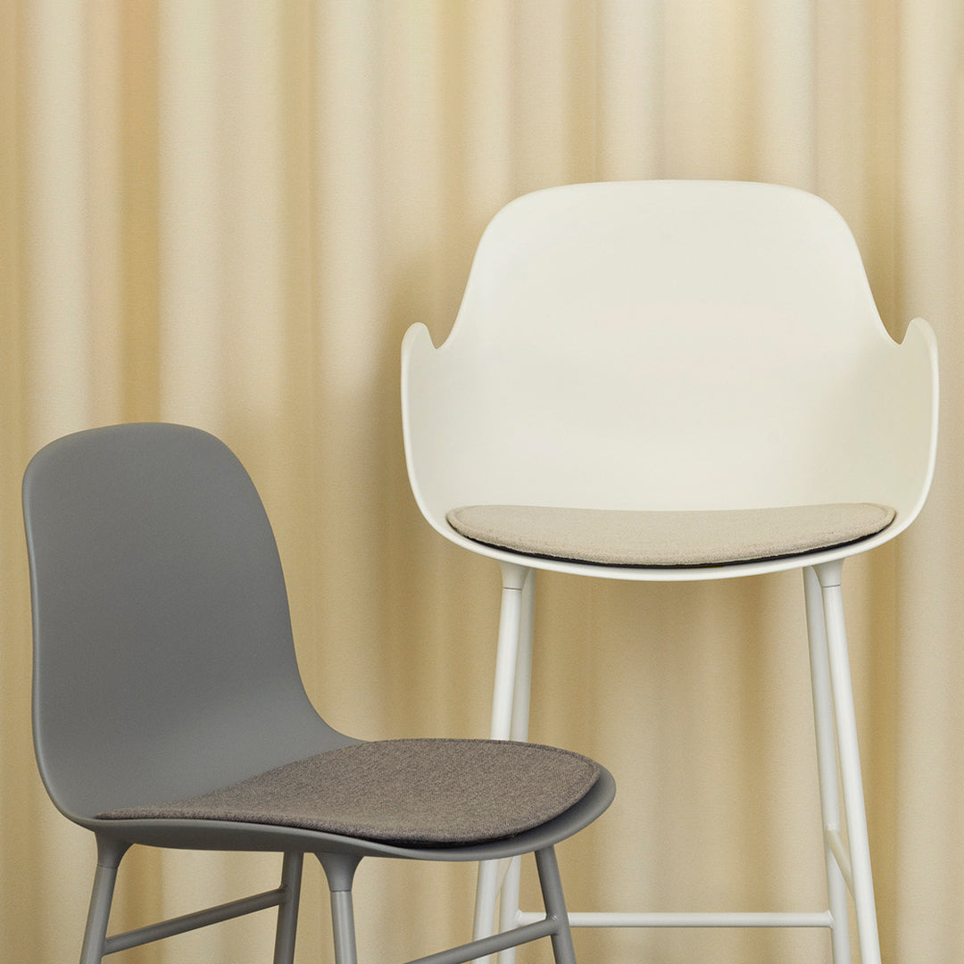 Two modern chairs: one sleek gray with a fabric seat, and a white high chair with a minimalist design, set against beige vertical stripes.