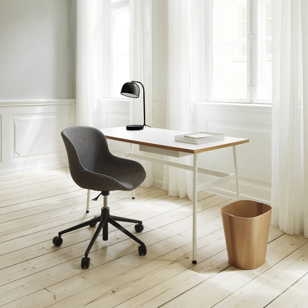 Gray ergonomic chair with clean lines, light wood desk, and soft beige accents in a bright, airy room.