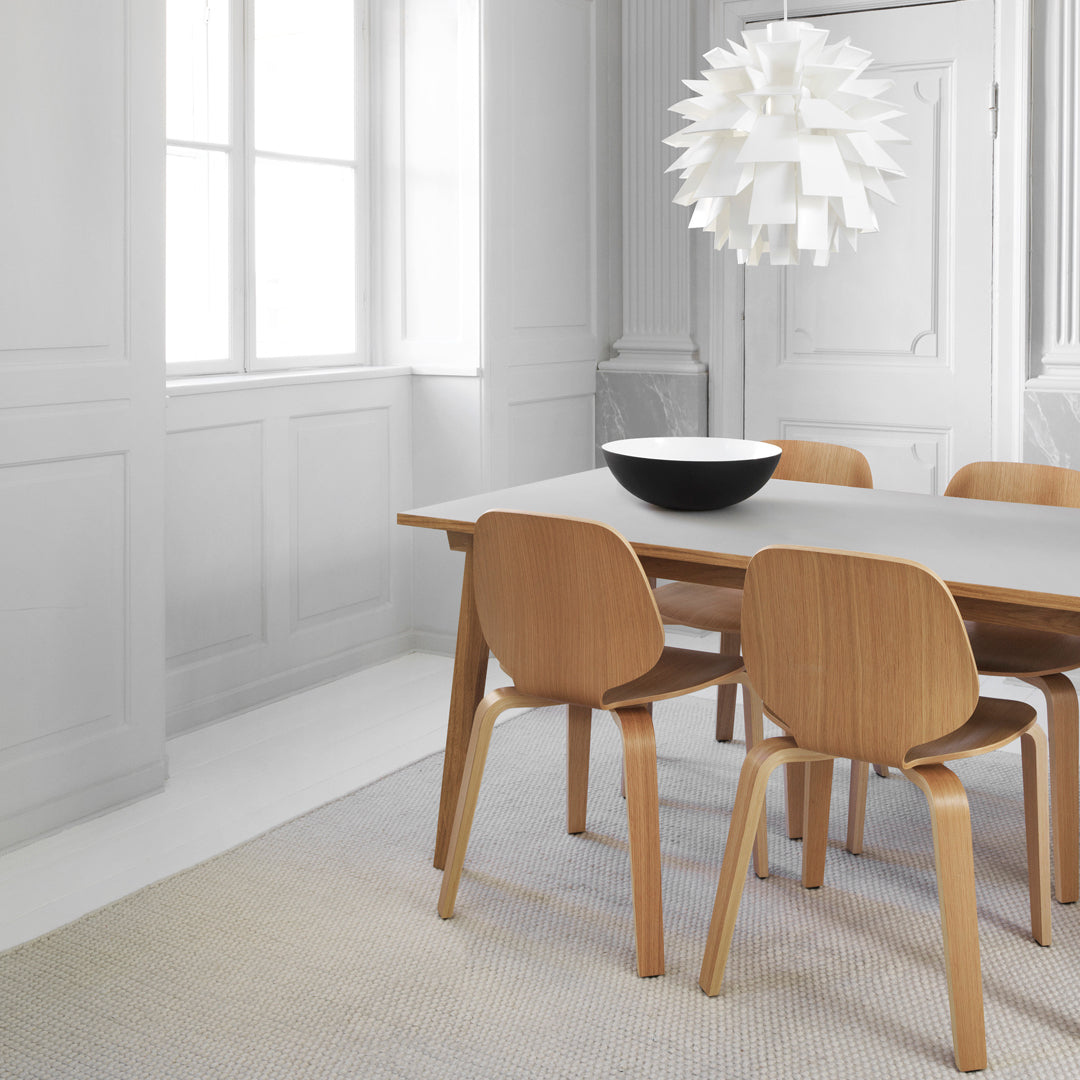 Modern dining room featuring a white round pendant light, natural wood chairs, and a sleek gray table.