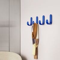Bright blue wall hooks displaying a cozy scarf in earthy tones, enhancing modern decor with playful patterns.