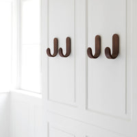 Brown wooden hooks on a sleek white wall, showcasing a modern and minimalistic design.