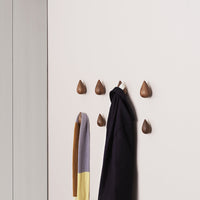 Stylish wall hooks in walnut finish with a smooth, teardrop design, paired with a gray, mustard, and black scarf.