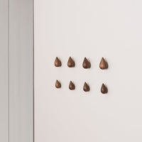 Brown teardrop wall hooks in varying sizes arranged in a neat pattern on a soft beige wall.
