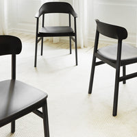 Black wooden dining chairs arranged on a light textured rug, featuring a minimalist design and sleek lines.
