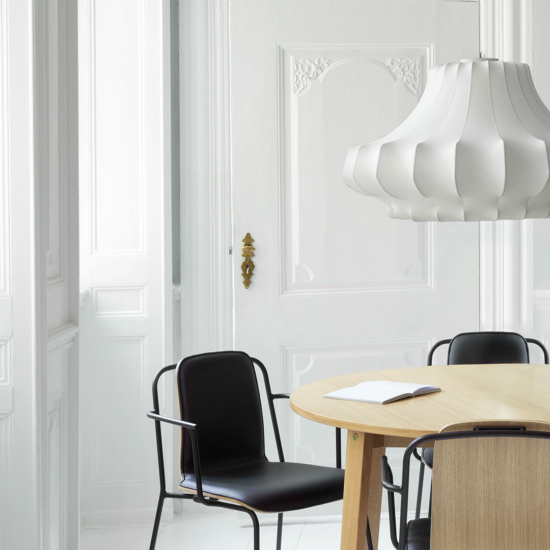 Minimalist white and black color scheme with a textured white lamp and natural wood table in a bright, airy setting.