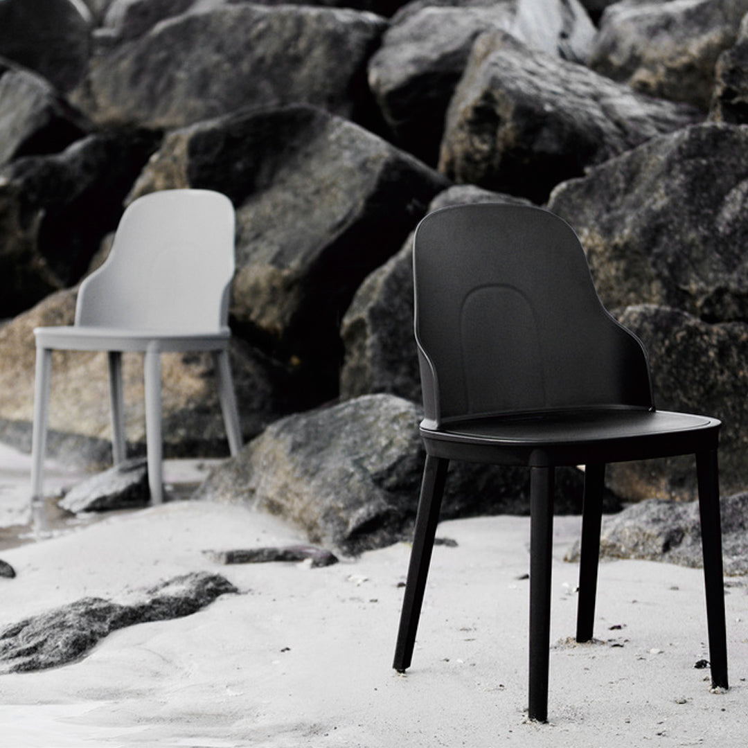 Modern chairs in sleek black and gray, featuring minimalist design against a rocky backdrop.
